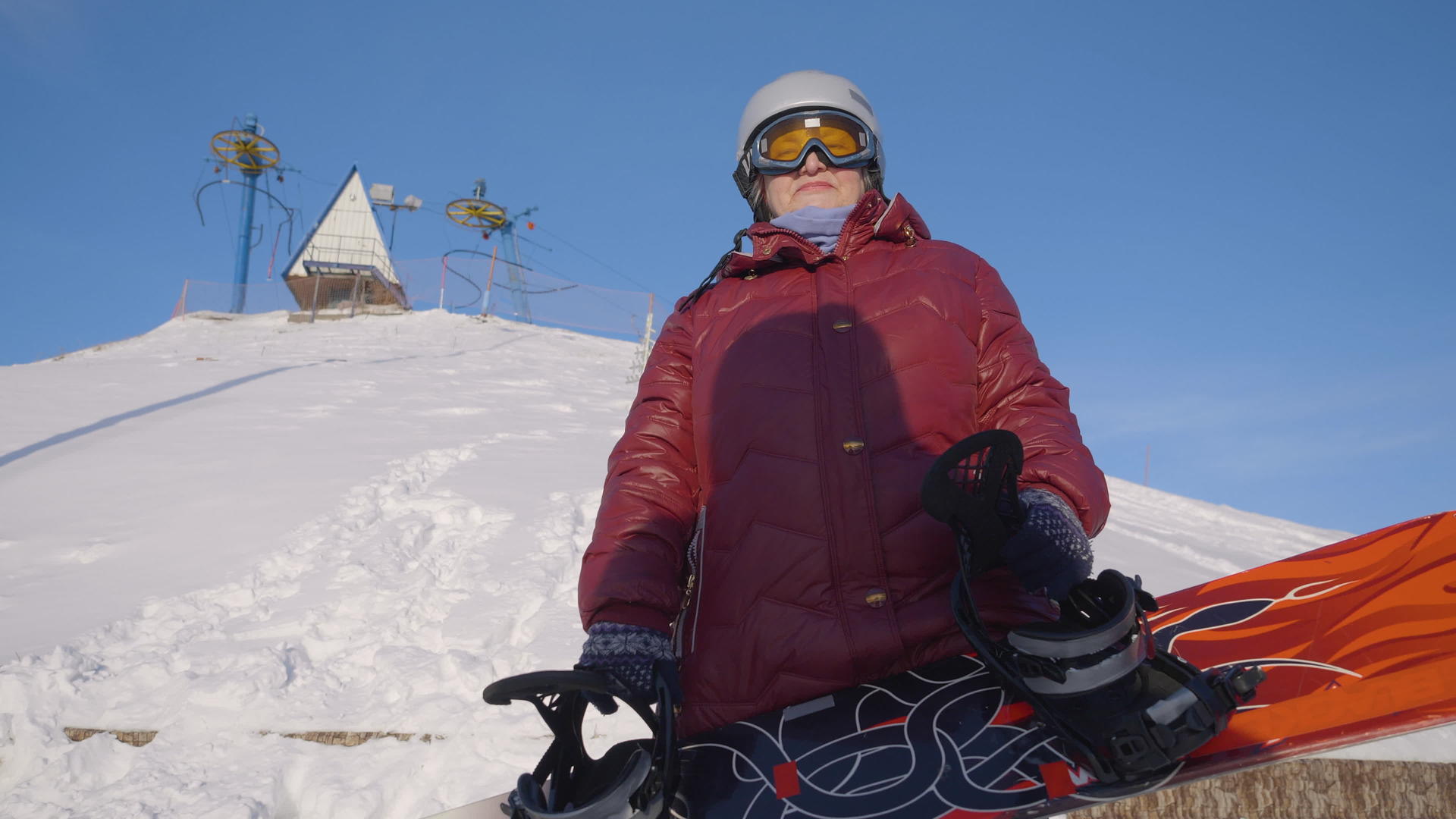 戴着滑雪板的资深妇女戴着头盔和眼镜穿着滑雪服站在滑雪场视频的预览图