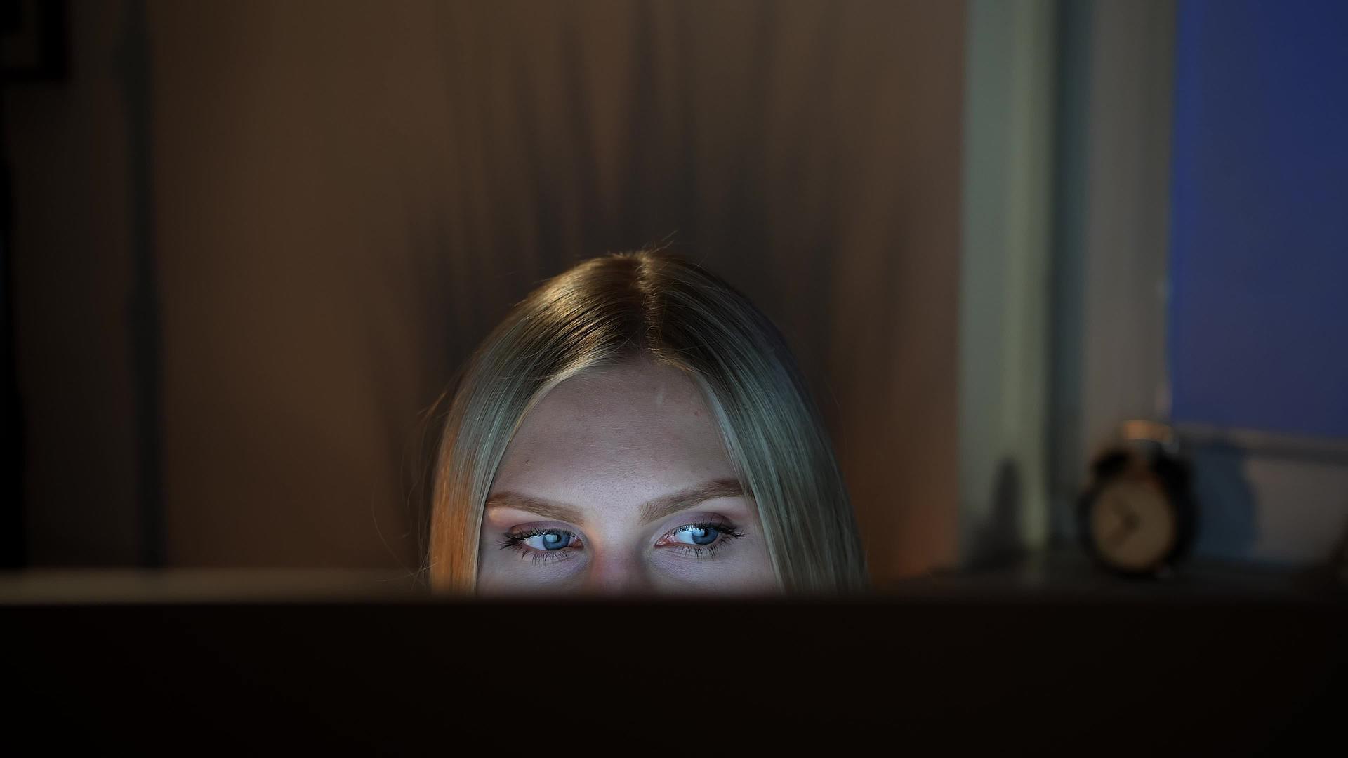 晚上偷看电脑显示器的漂亮女人晚上坐在电脑前看电脑视频的预览图
