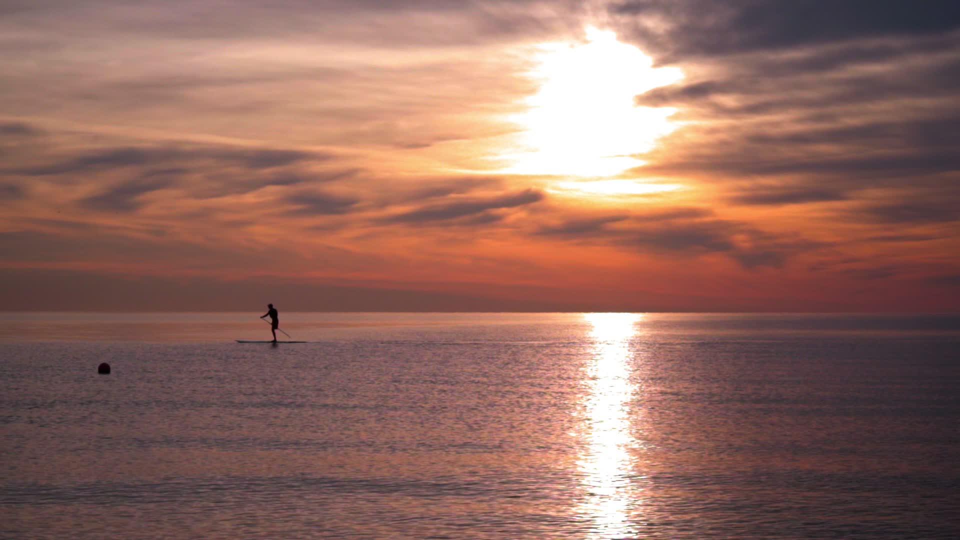日落时在冲浪板上人类的双轮长鸟飞过大海视频的预览图