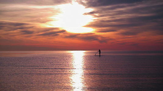 日落时有人在冲浪板上划船视频的预览图