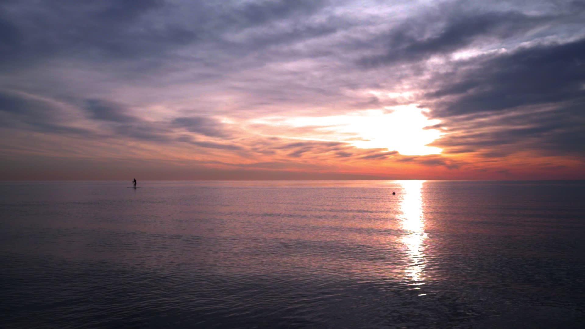 海洋日落日落海洋冲浪板上的人平静的海水日落视频的预览图
