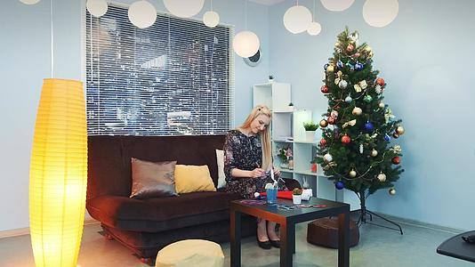 美丽的女人在圣诞节写信坐在那里Xmas沙发上的树视频的预览图