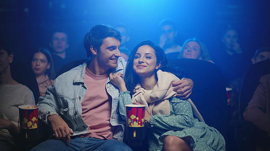 年轻夫妇在电影院看电影讨论剧情视频的预览图