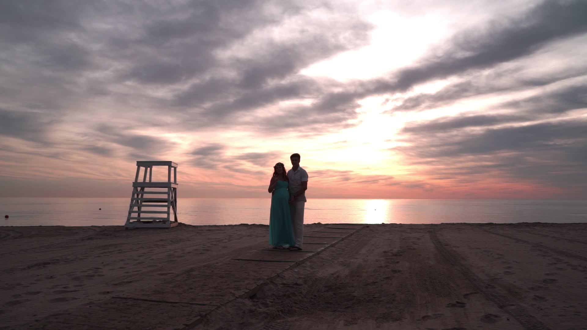 怀孕夫妇在日落时谈恋爱的概念海边的浪漫情侣视频的预览图