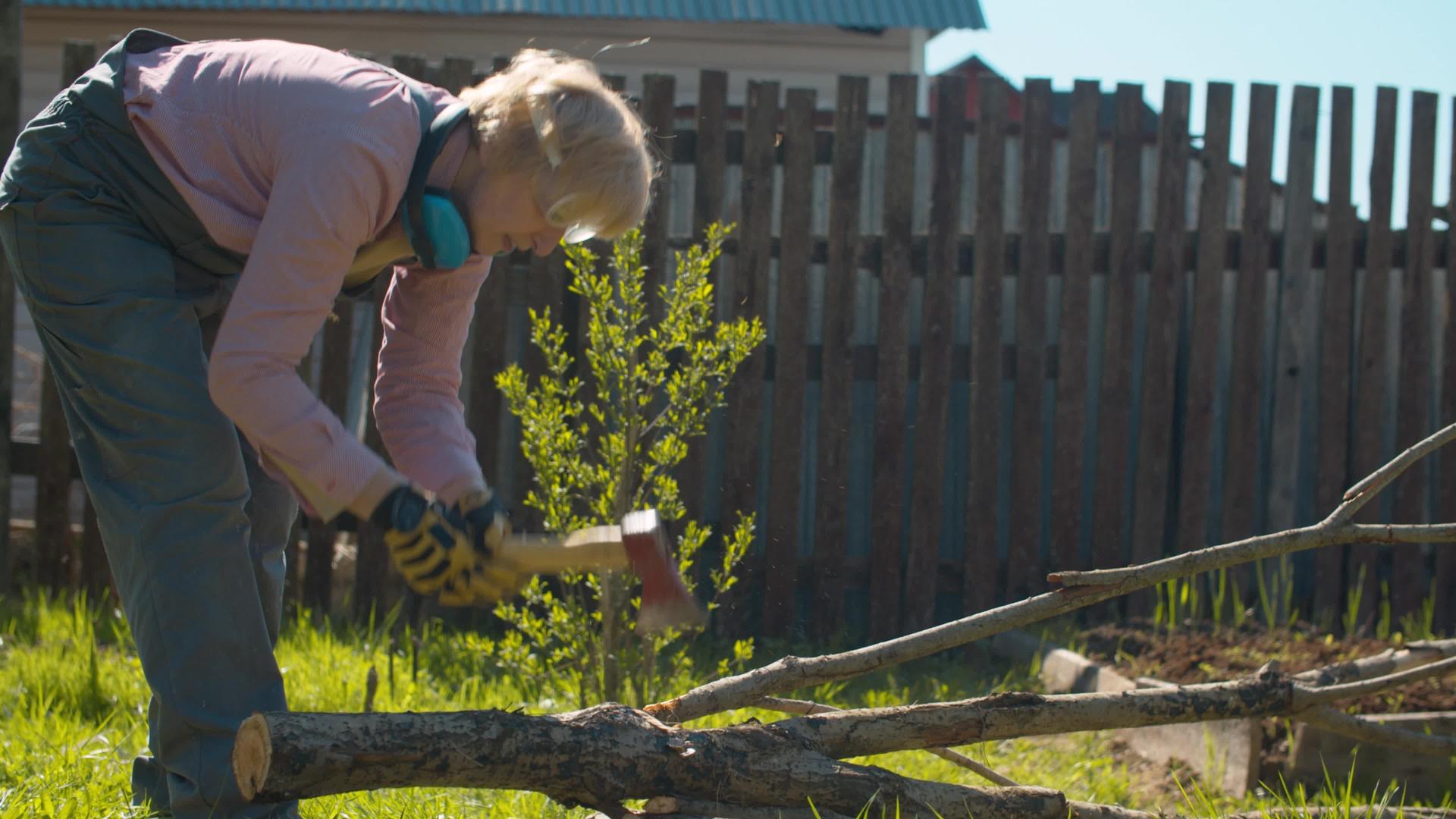 院子里的女人用斧头砍树枝视频的预览图