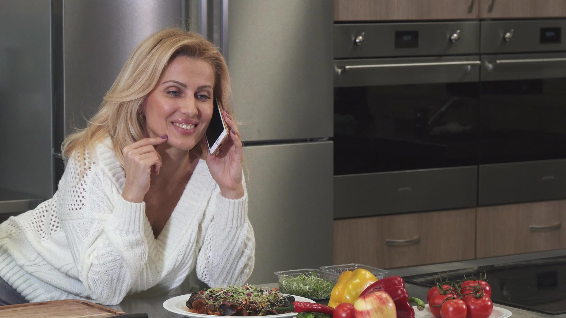 令人惊叹的成熟快乐女人在厨房电话里聊天视频的预览图