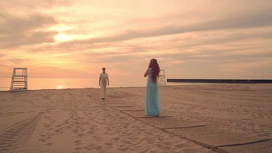 黄昏时分情侣们在海滩上相遇一起漫步视频的预览图