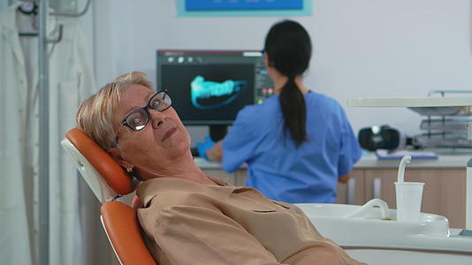 高级女性在牙科诊所看相机等待相机视频的预览图
