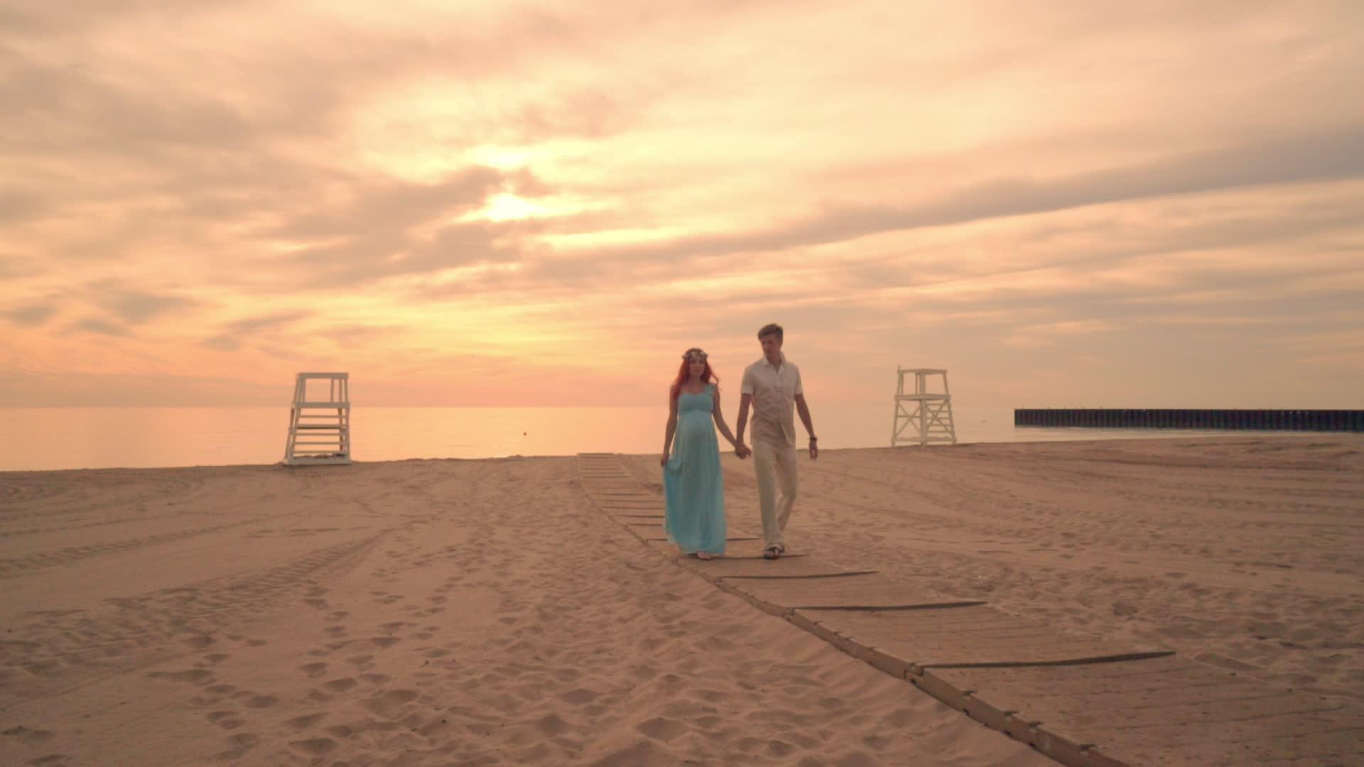 爱情夫妻在日落时在海边散步晚落时在海边怀孕视频的预览图