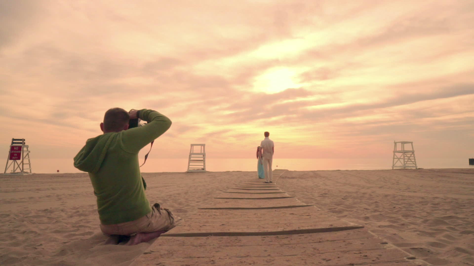 摄影师在日落的海滩上拍摄情侣照片摄影师海滩视频的预览图