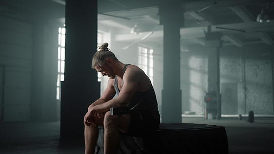 男性健身运动员在运动之间坐在轮胎上休息视频的预览图