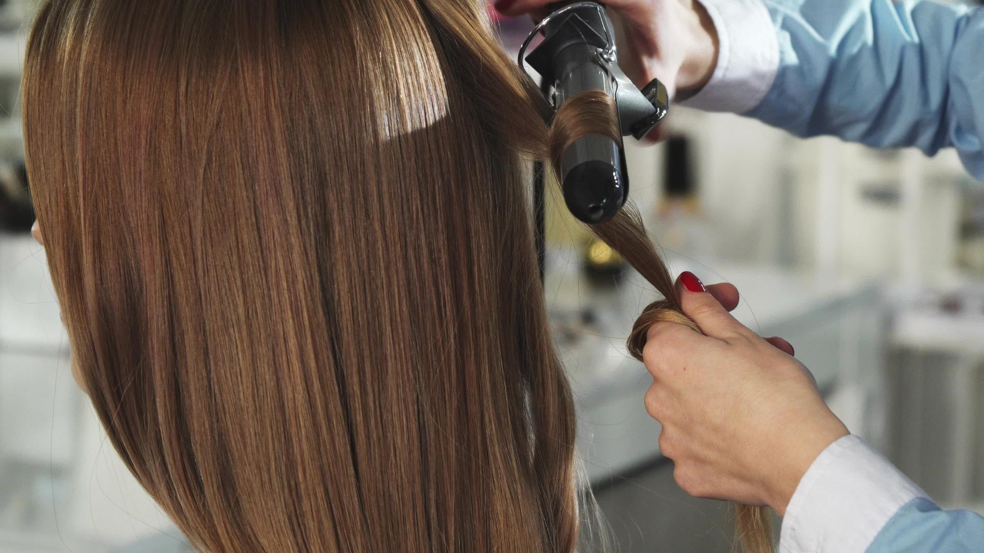 一个女人被一个专业的发型师卷起头发然后抬起头来视频的预览图