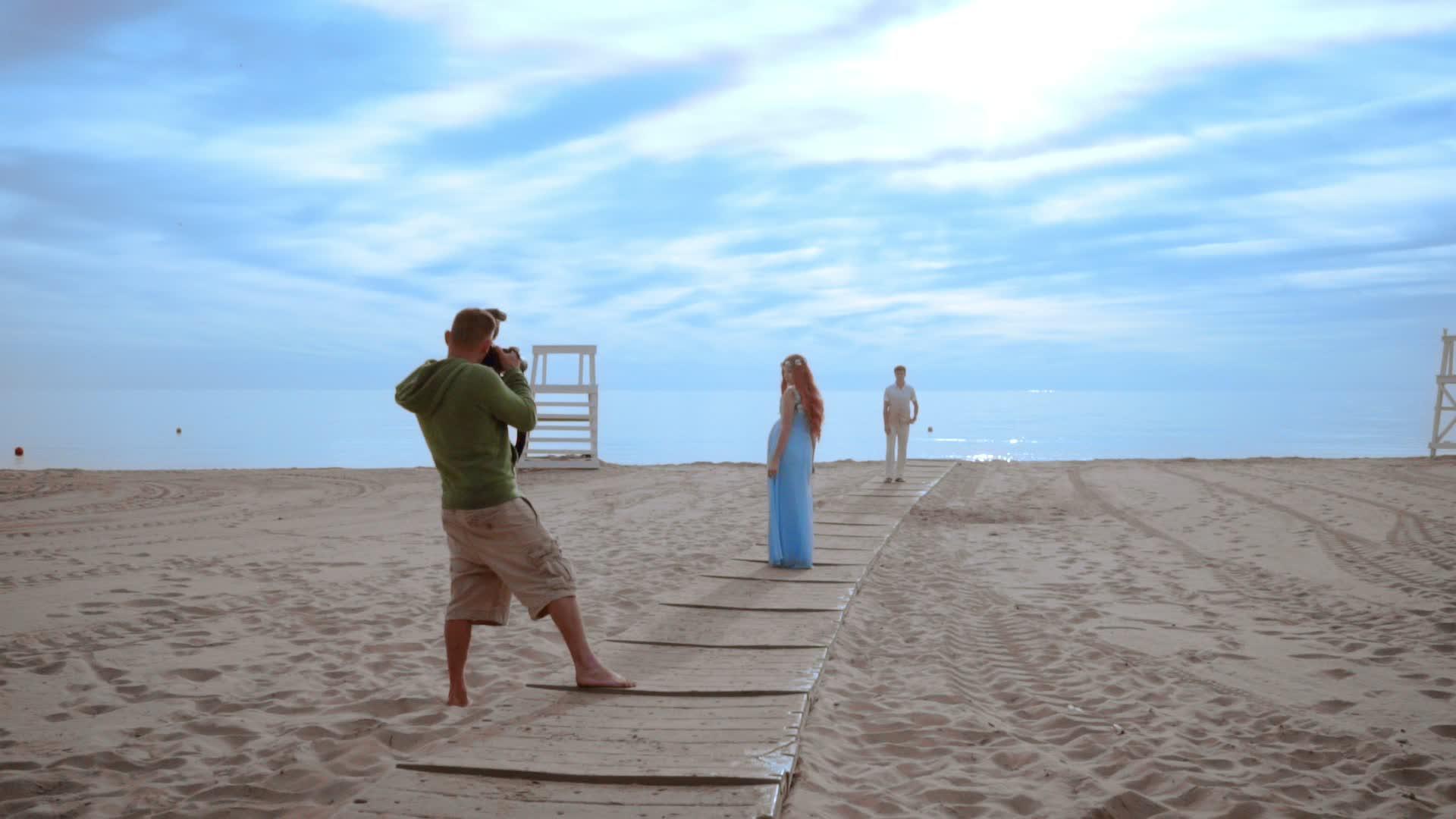 专业摄影师在海滩拍摄情侣照片视频的预览图