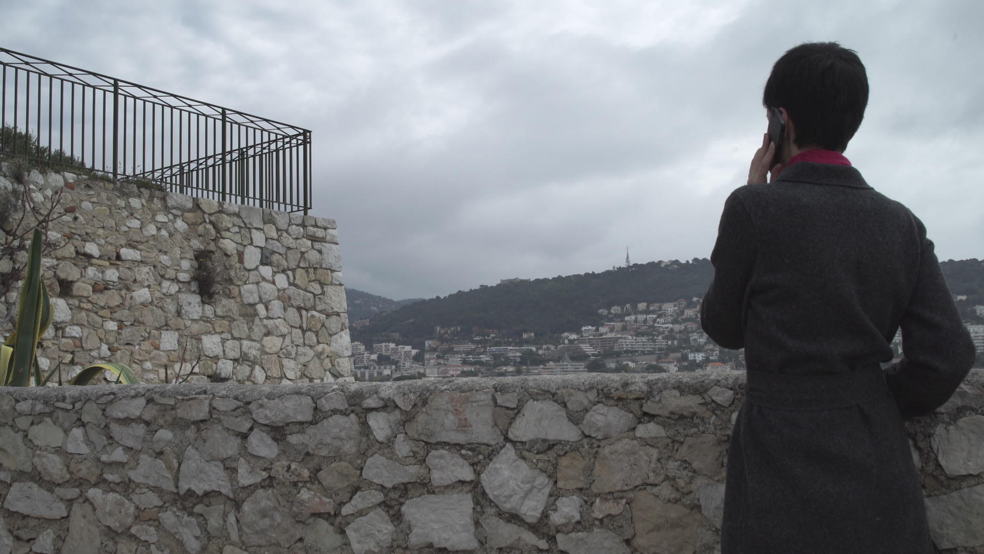 女人用智能手机站在石墙附近视频的预览图