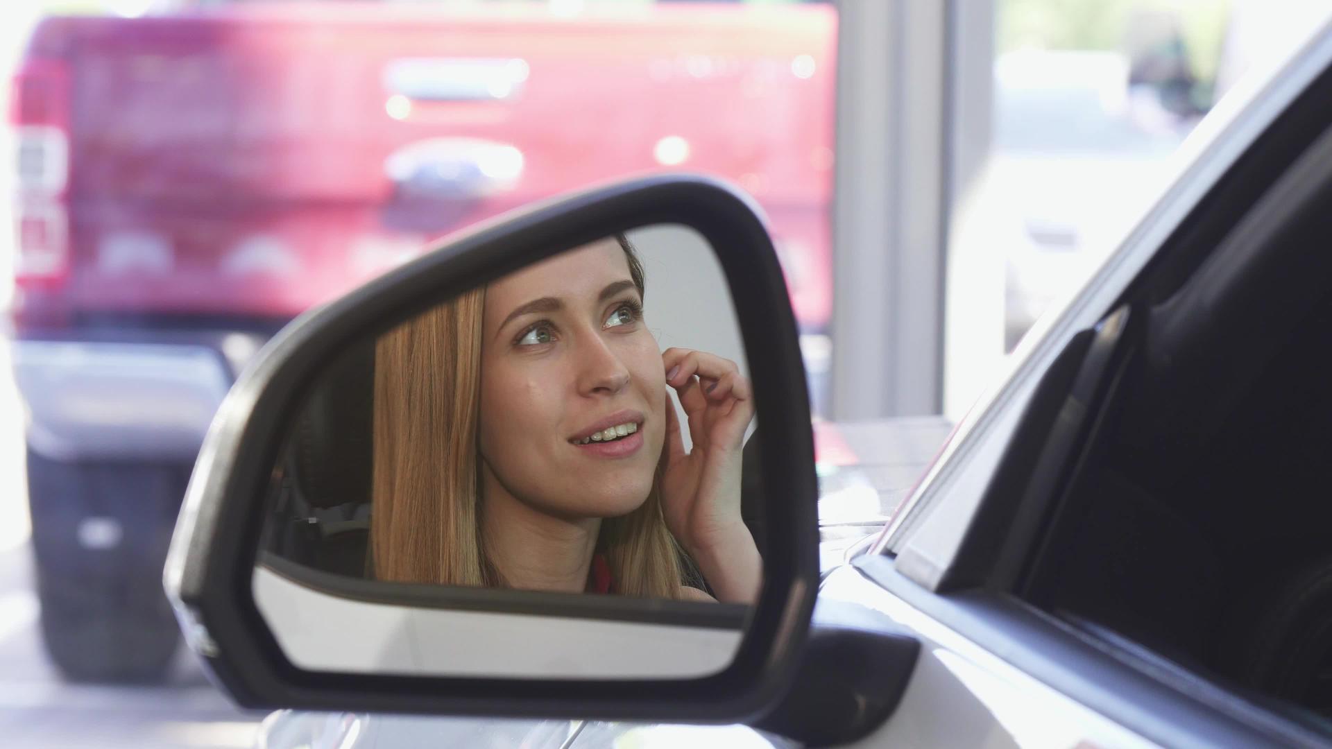 美丽的女司机在镜子旁边的相机上微笑视频的预览图