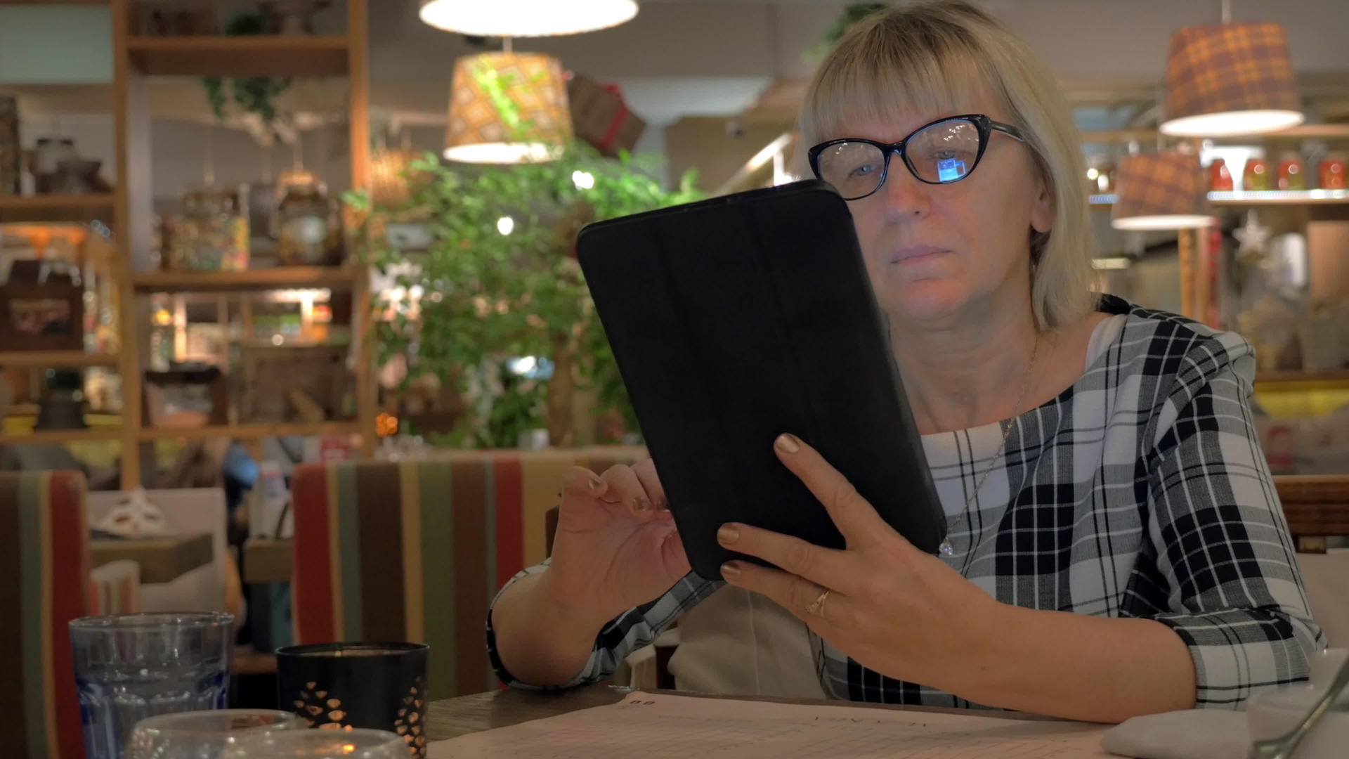 年长妇女浏览咖啡馆触摸垫视频的预览图