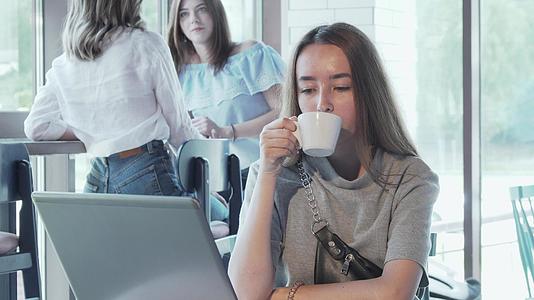 快乐的年轻女性喜欢在咖啡店用笔记本电脑工作视频的预览图