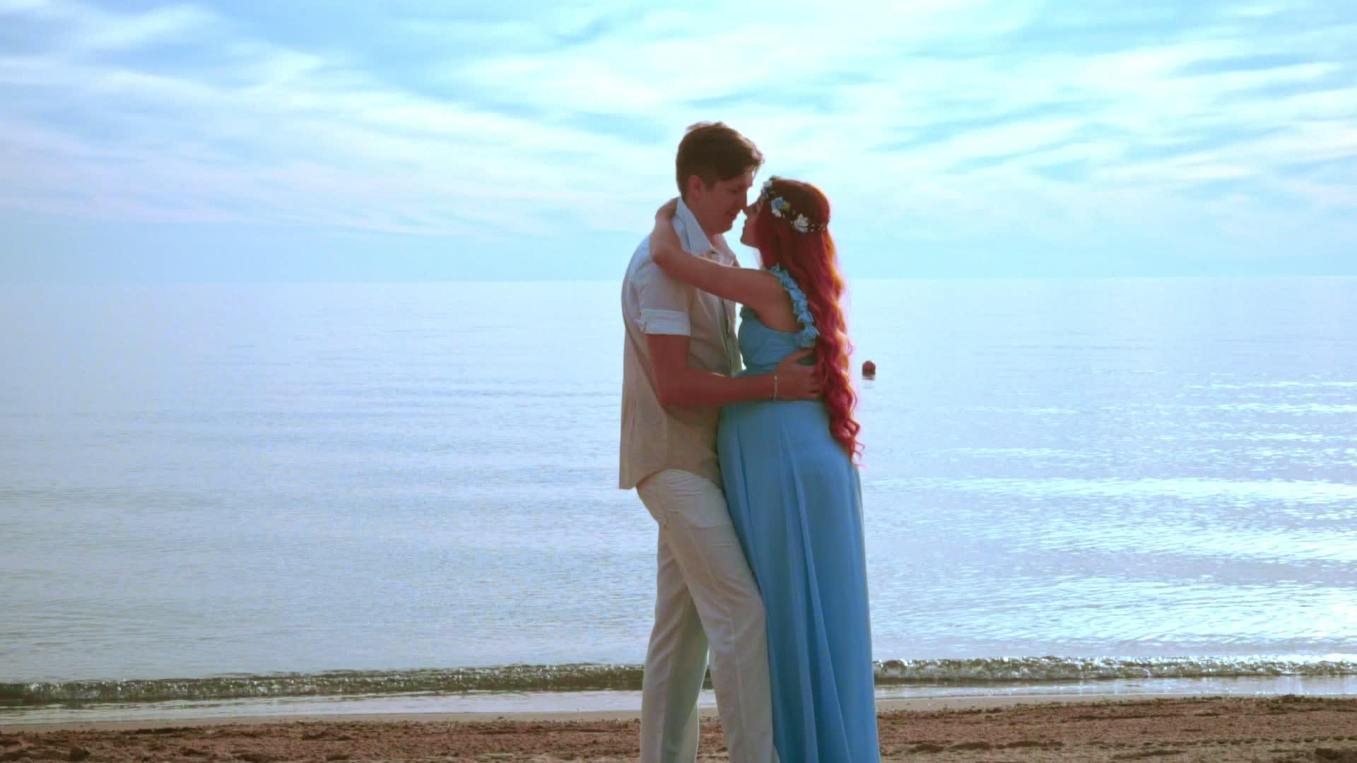 年轻人在海边亲吻怀孕夫妇快乐的情侣海滩视频的预览图