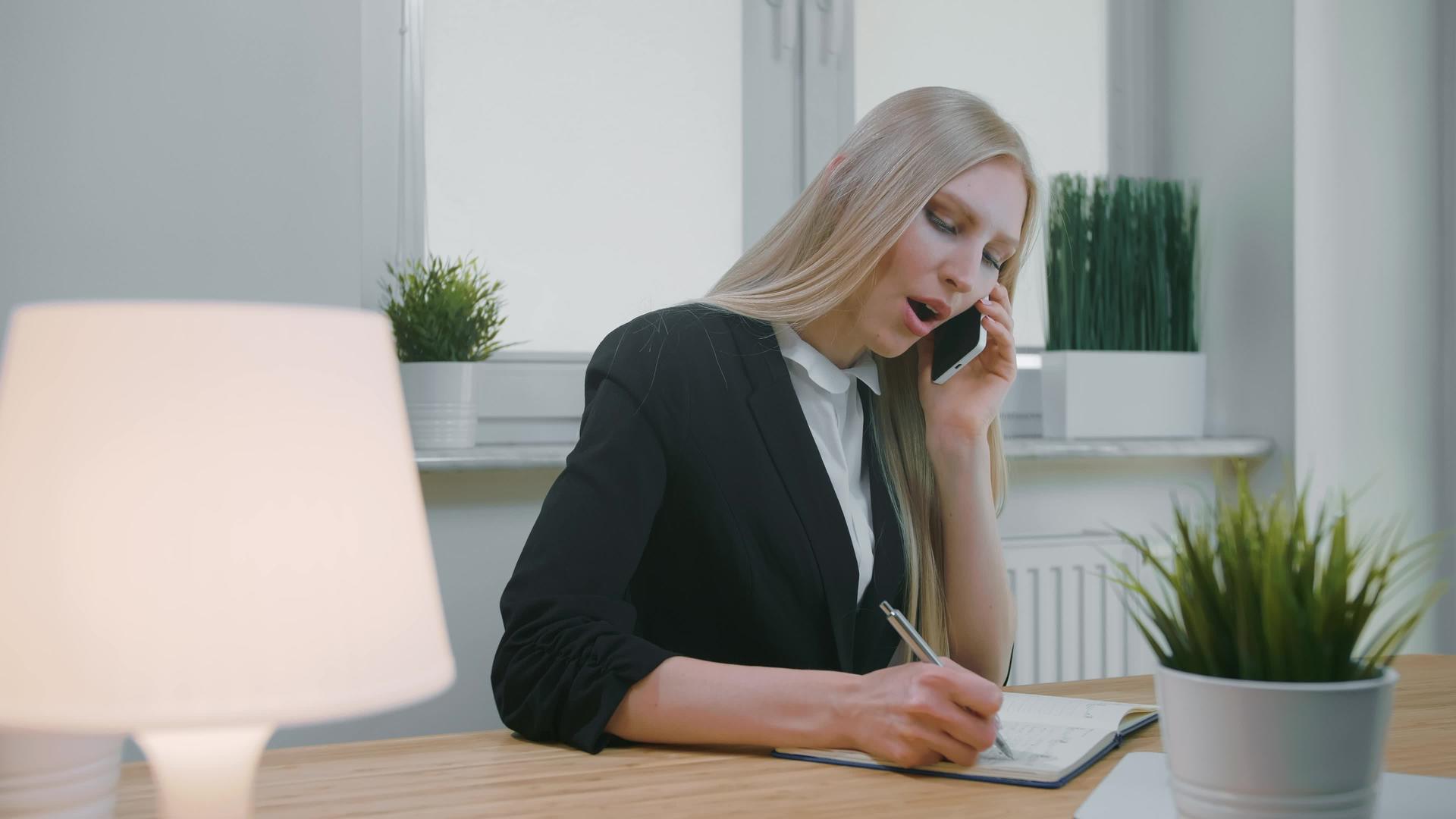 商界女强人优雅的年轻金发女性在办公室谈论智能手机视频的预览图