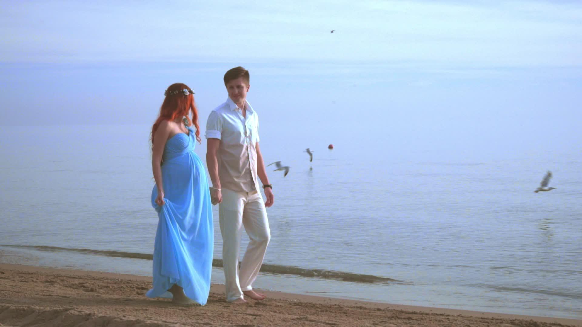 一对怀孕的夫妇在海边的一对夫妇在海滩上散步的一对情侣视频的预览图