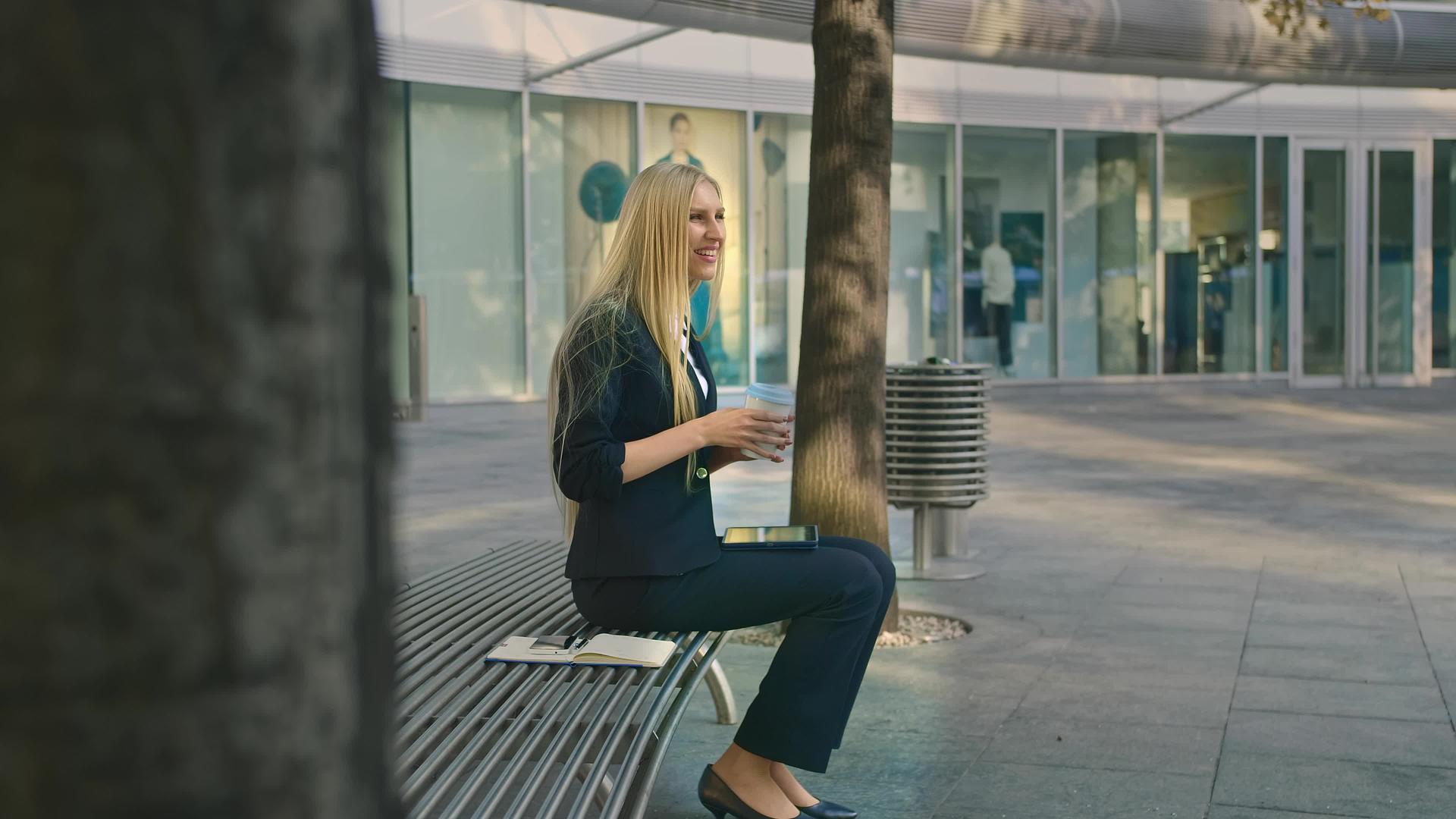 正规的年轻女性坐在长椅上喝咖啡视频的预览图
