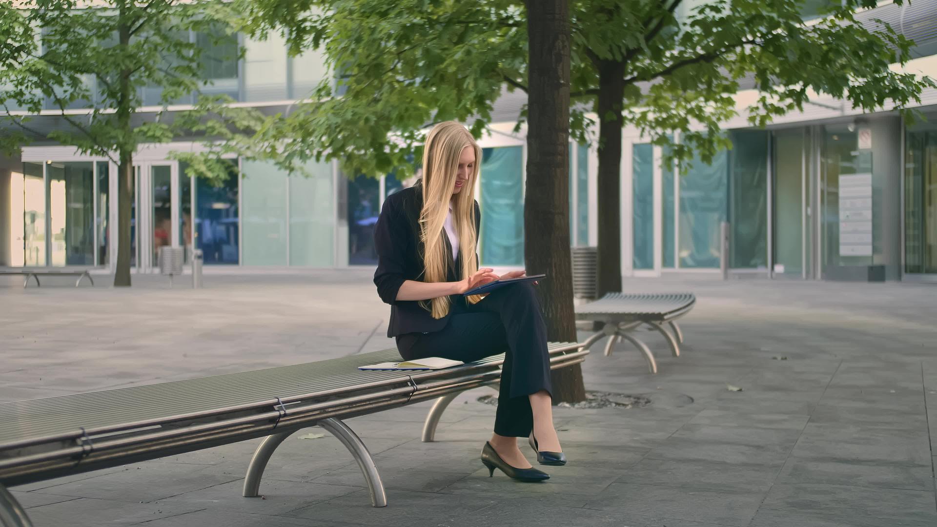 年轻女士在长椅上使用平板电脑视频的预览图