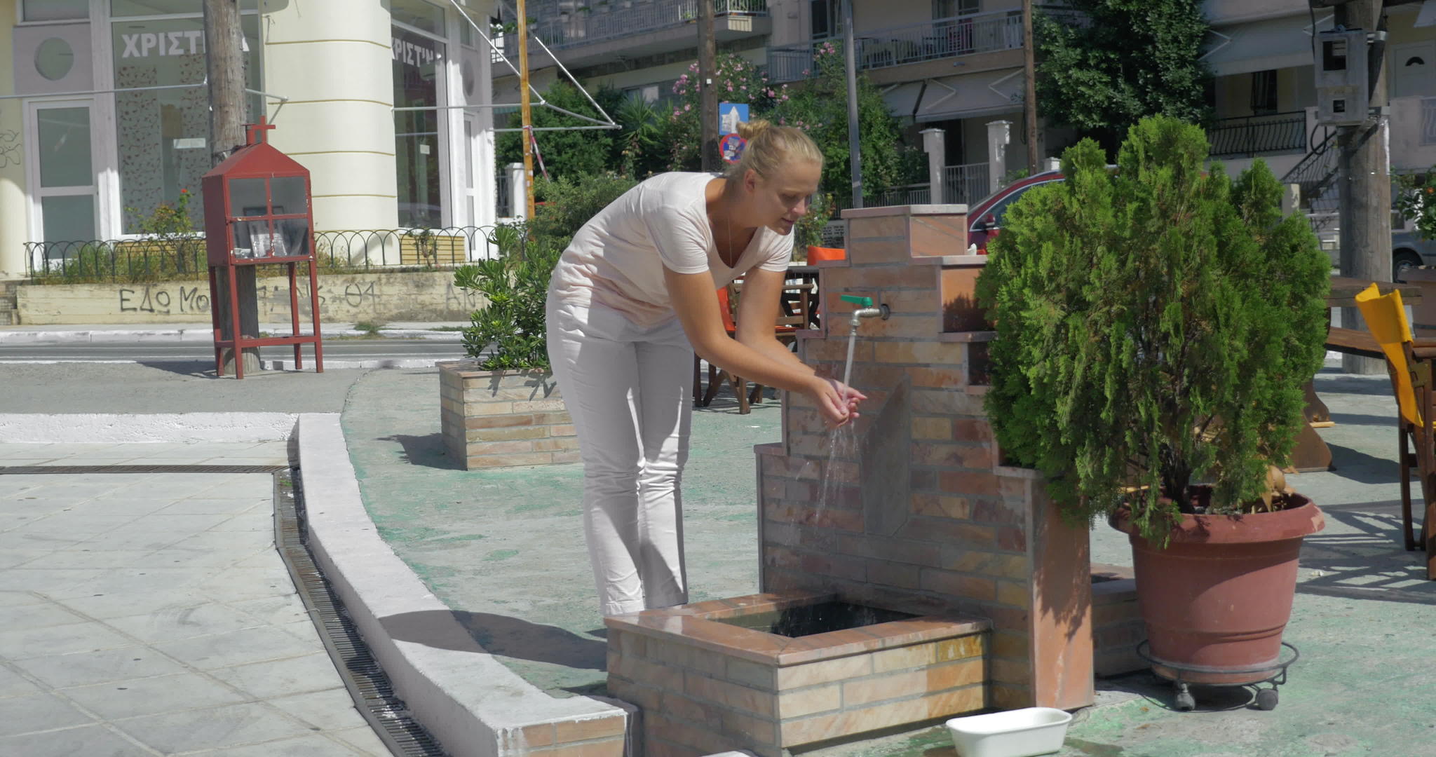夏天年轻女子在比雷埃夫斯街的公共喷泉里洗脸视频的预览图