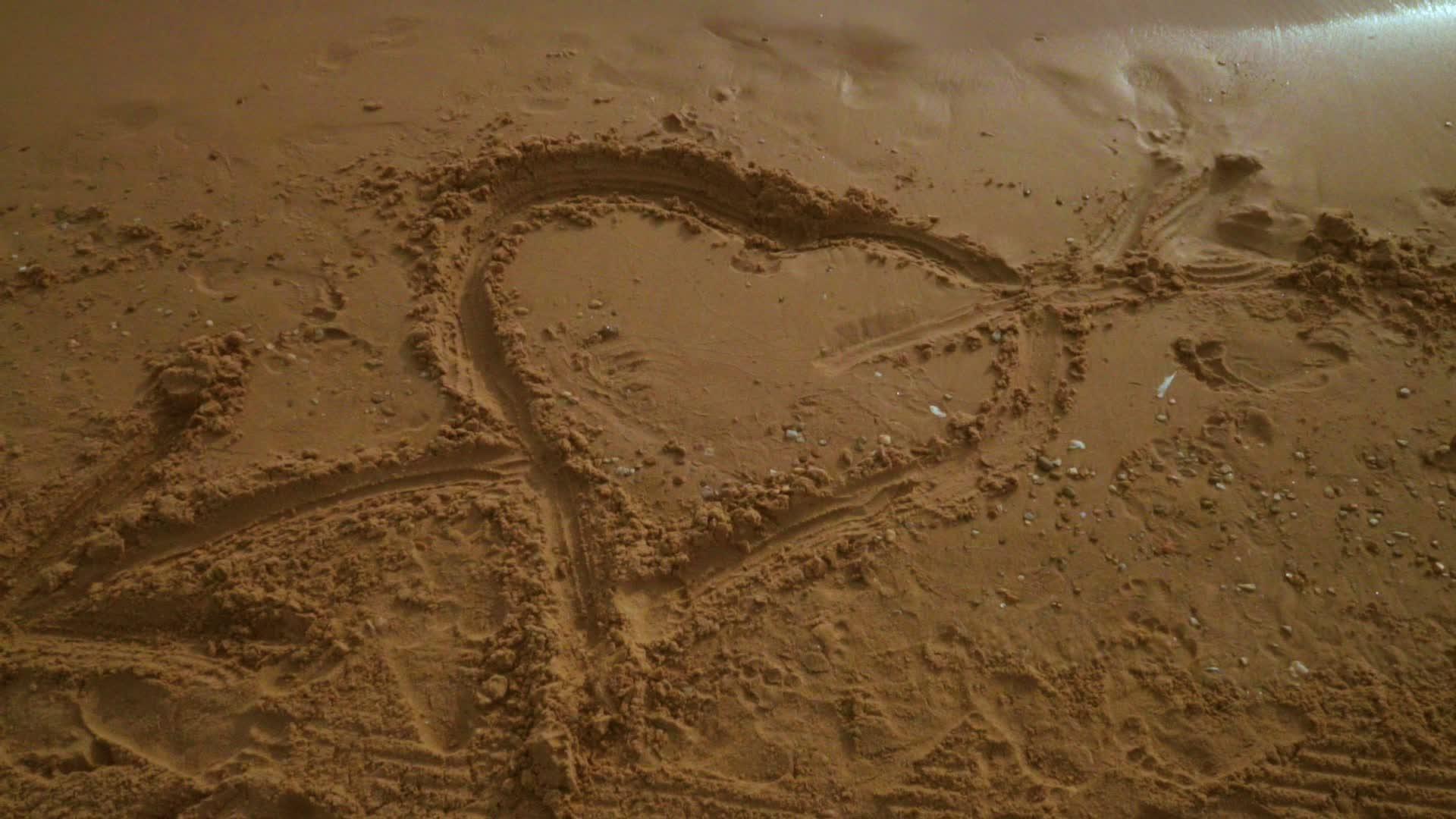 心沙在沙滩上画心从沙上的心形标志到天空的平移视频的预览图