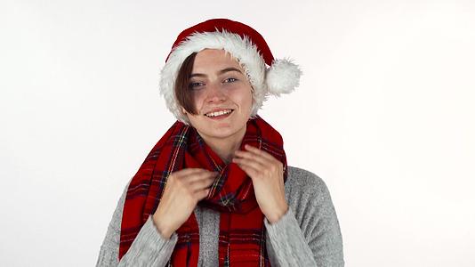快乐的女人戴着圣诞帽子和冬季围巾对着相机微笑视频的预览图
