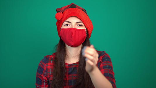 一名戴着圣诞红帽和医用防护口罩的妇女看着镜头给了一个飞吻视频的预览图