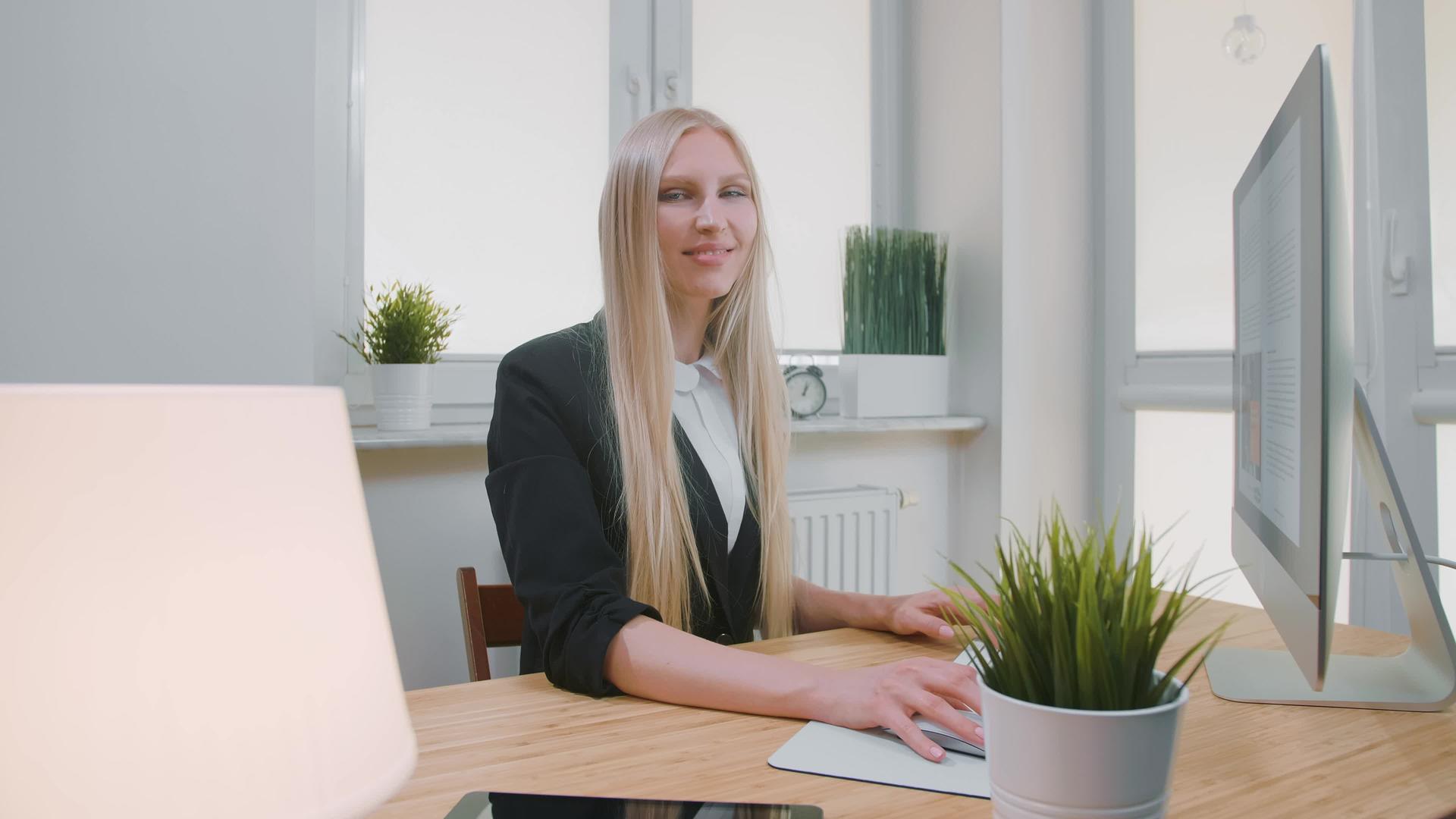 微笑的女人在办公室的电脑上工作漂亮的年轻金发女人坐在那里视频的预览图