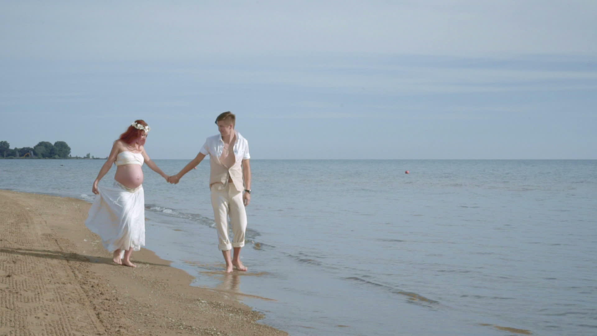 一对怀孕夫妇在海滩上漫步海滩上的孕妇视频的预览图