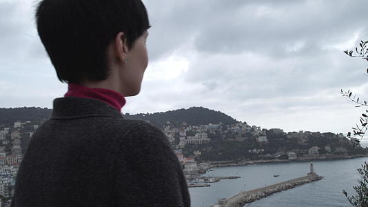一个穿着灰色羊毛外套的女人看着城市风景视频的预览图