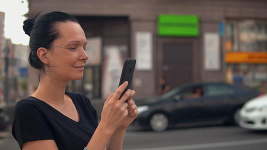 在夏季镇使用流动手机的黑发女士视频的预览图