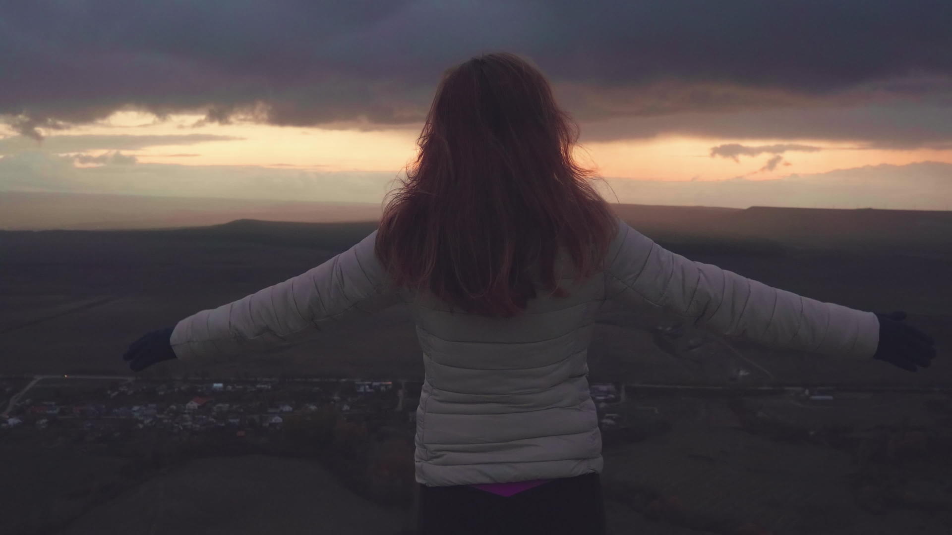 那个女人举起手在山顶的山风中吹着她的头发她在黄昏时空中慢慢地飞翔视频的预览图