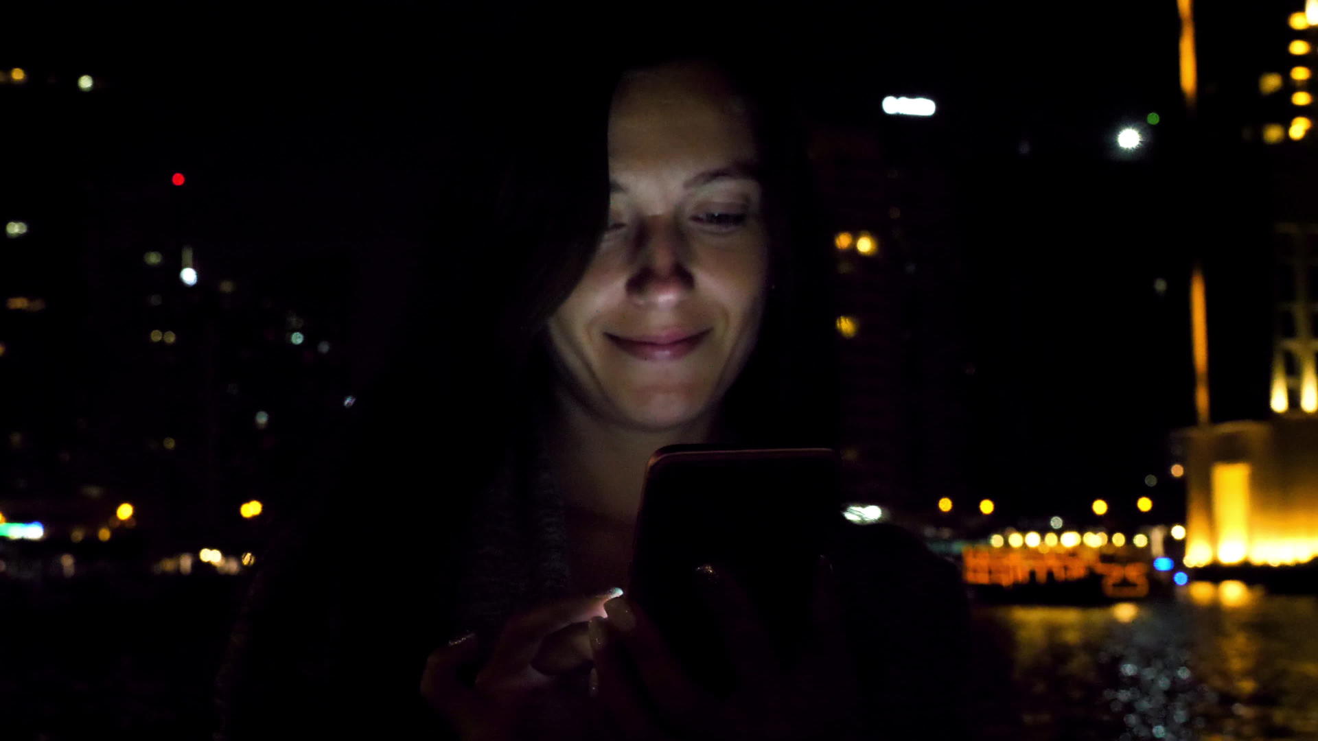 漂亮的女人晚上用智能手机视频的预览图