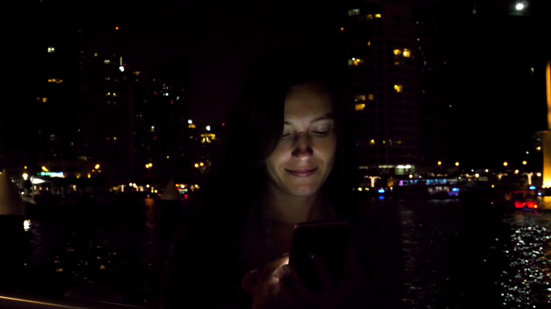 有吸引力的女性在夜间使用智能手机视频的预览图