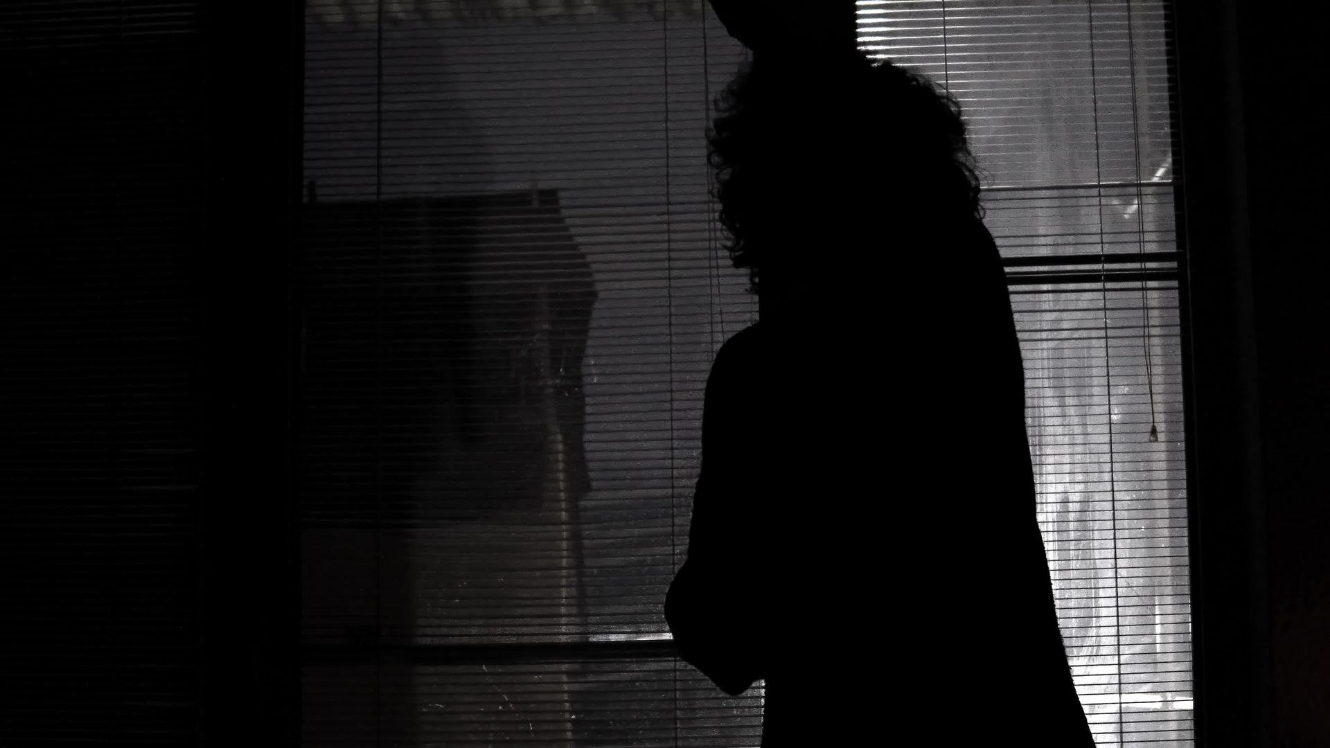 晚上一个害怕的孤独的女人关上窗帘在街灯下视频的预览图