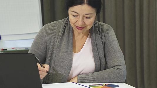 高级商业女性在笔记本电脑上工作时做笔记视频的预览图