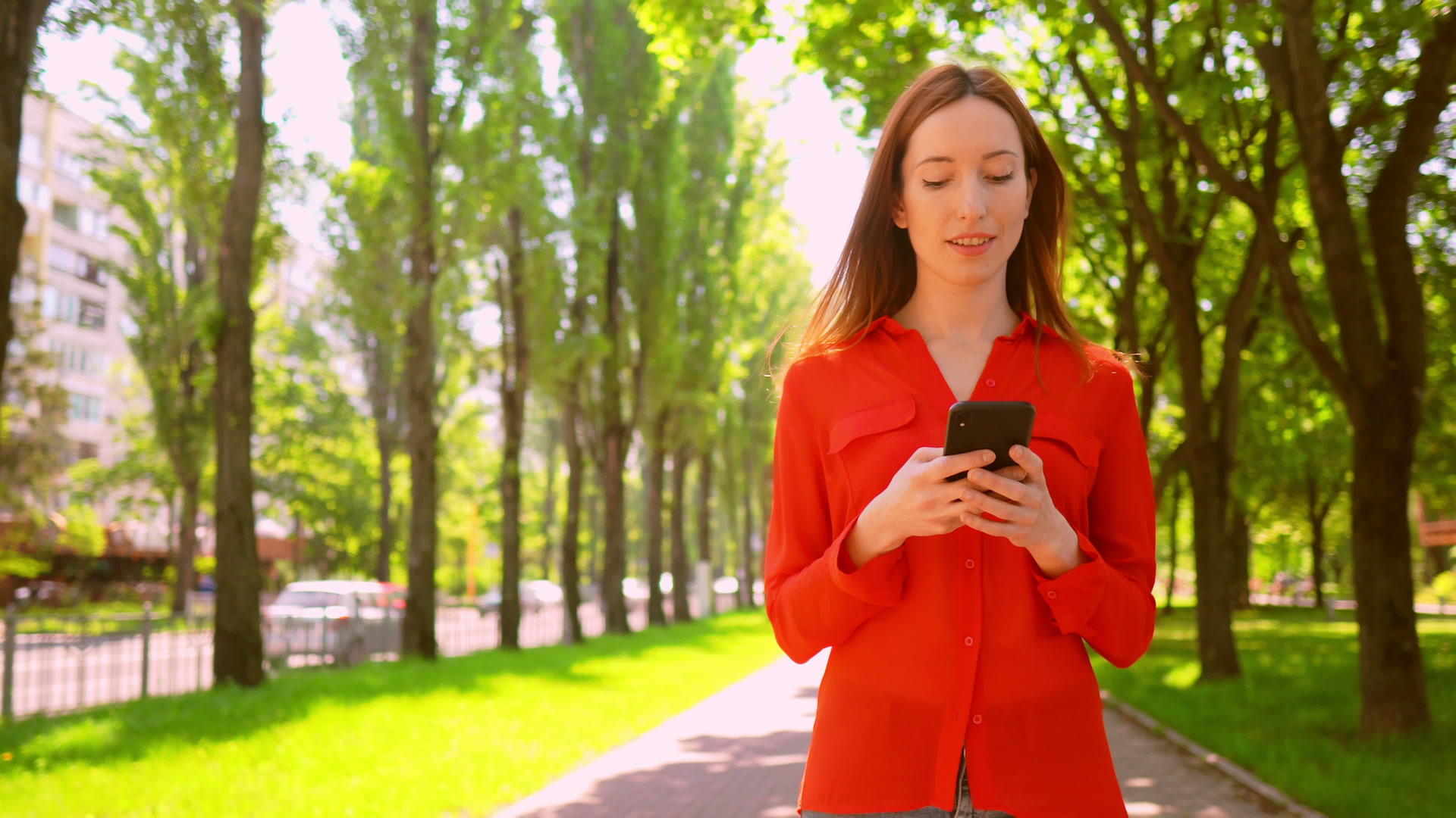 漂亮的红发女人在公园散步发短信视频的预览图
