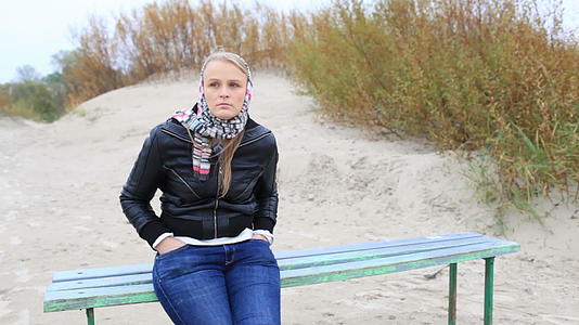 年轻女孩坐在海边的长椅上视频的预览图