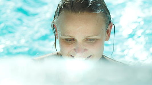 在游泳池清澈的蓝色水中快乐的年轻女子视频的预览图