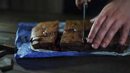木桌上的人切蛋糕在厨房里做巧克力蛋糕视频的预览图