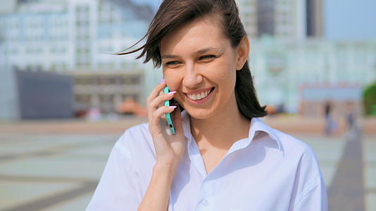 特写肖像快乐开朗的女性微笑着使用手机城市背景视频的预览图