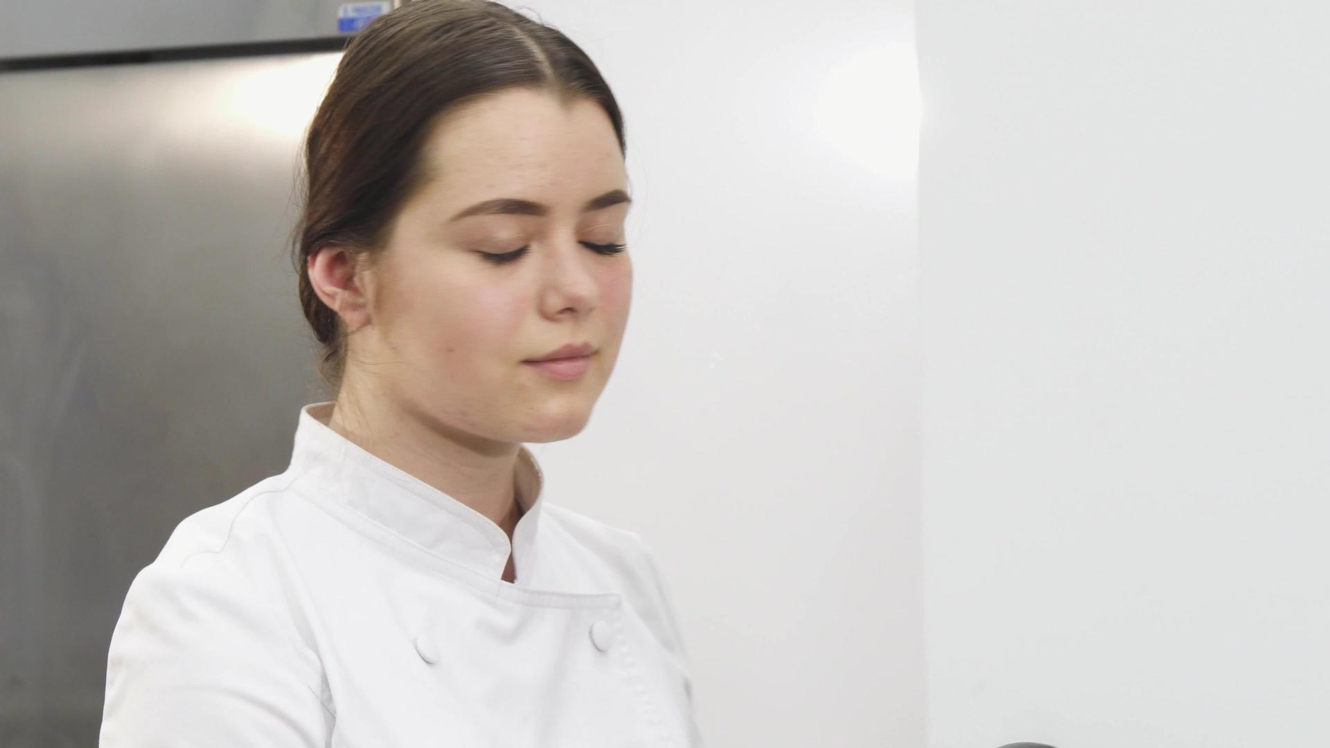美丽的女厨师在厨房工作时对着相机微笑视频的预览图