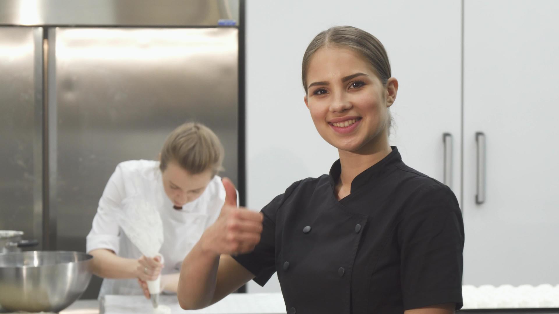 快乐的女厨师在厨房里微笑着露出拇指视频的预览图