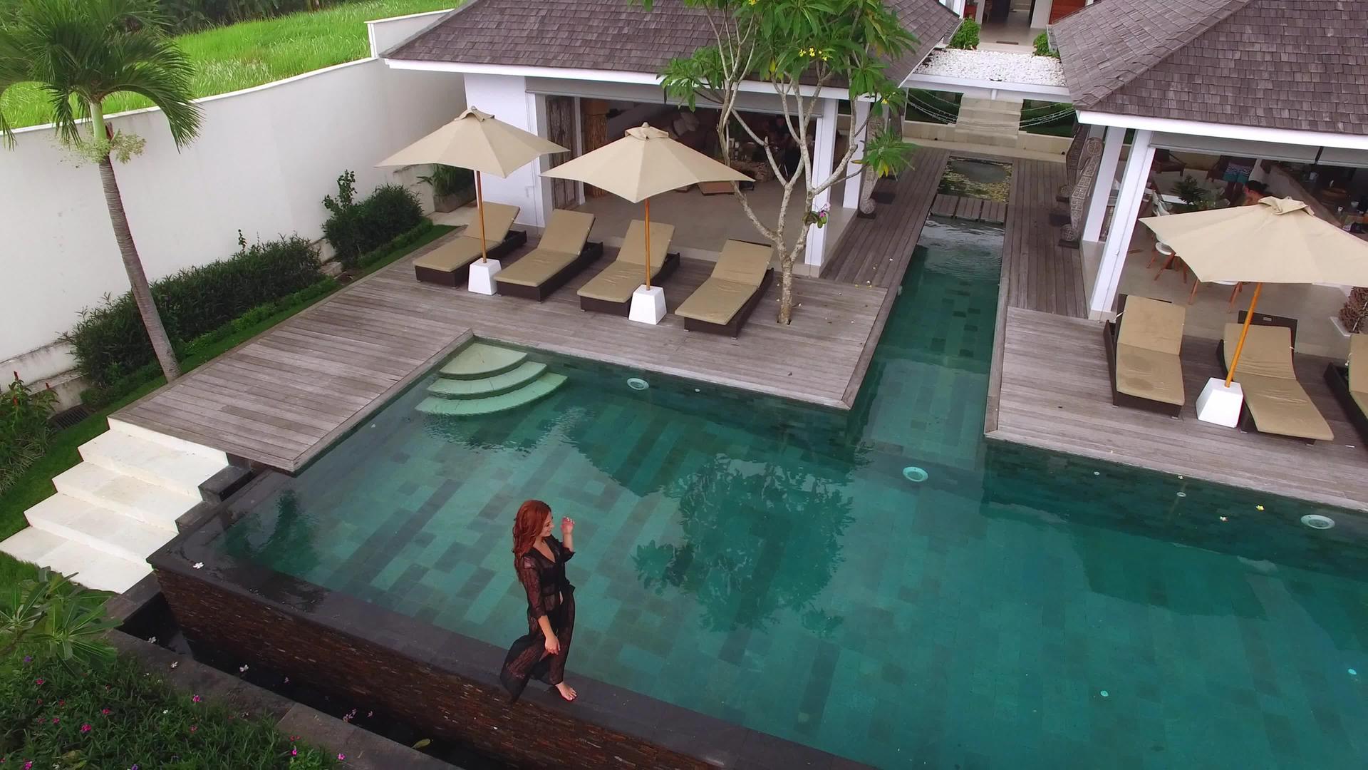 穿着黑色内衣的年轻性感女性走在豪华别墅游泳池附近视频的预览图