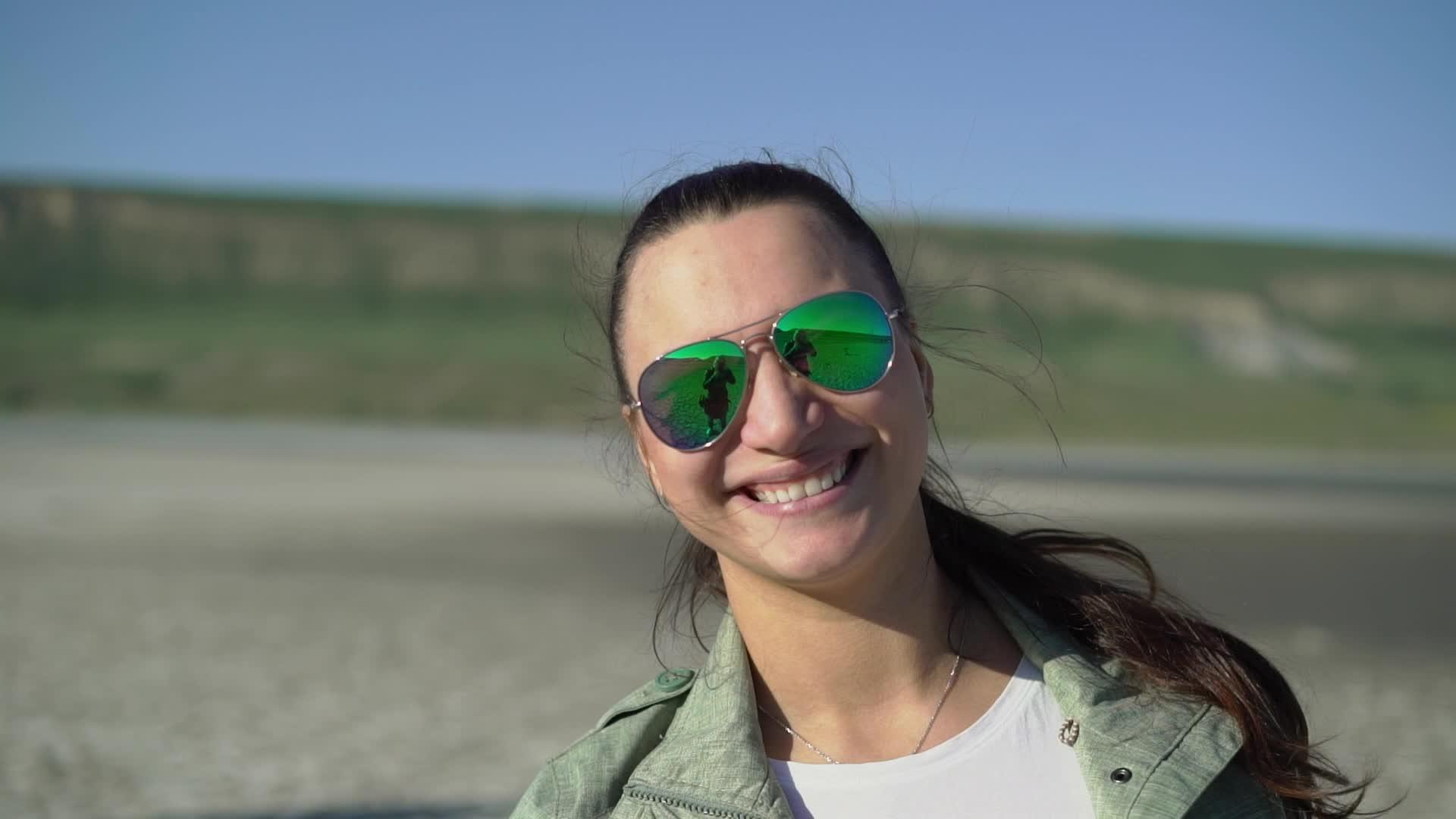 年轻女子戴着绿色太阳镜微笑视频的预览图
