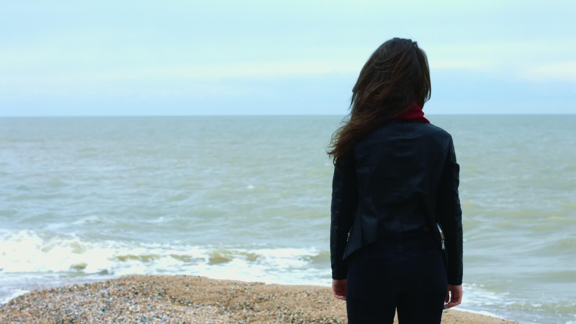 在沙滩上行走时年轻女子摸着棕色的头发随风而动视频的预览图