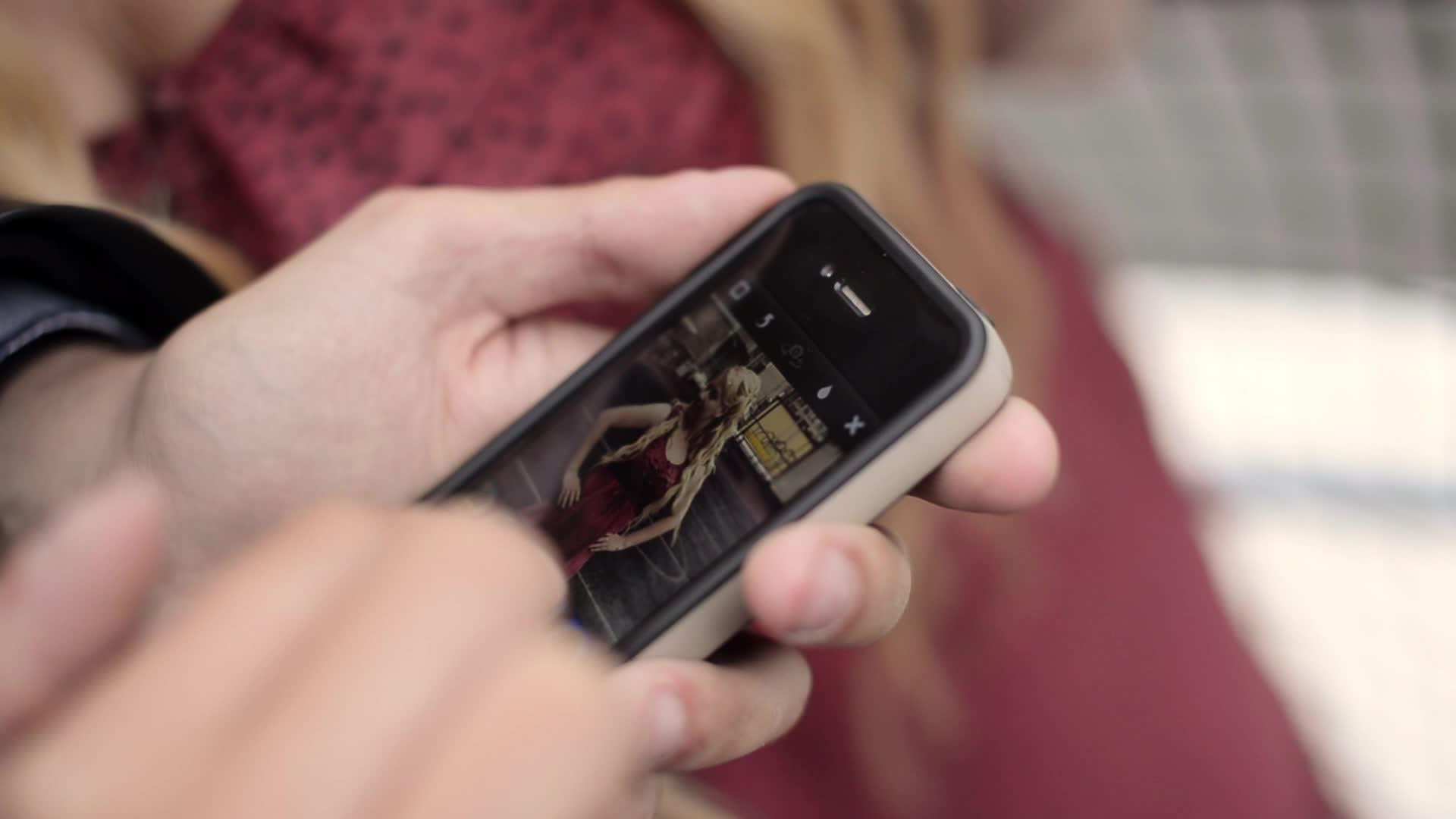年轻男子用手机拍摄女友在街上玩得开心的手机照片视频的预览图